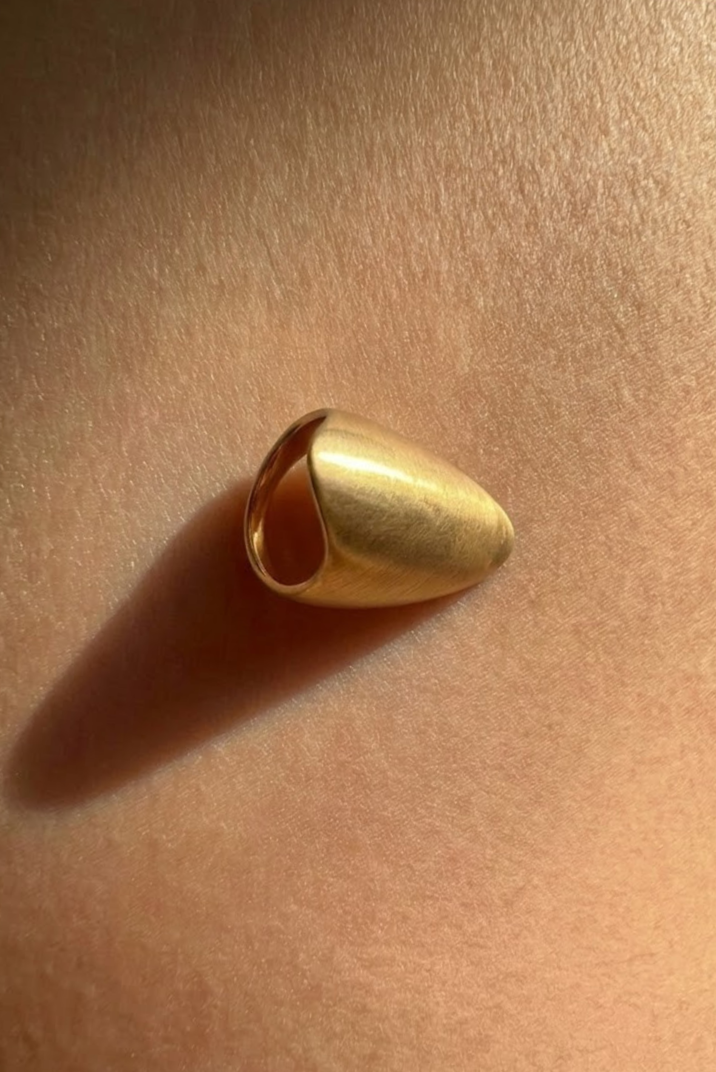 A bold gold ring with a fluid shape shown on its own