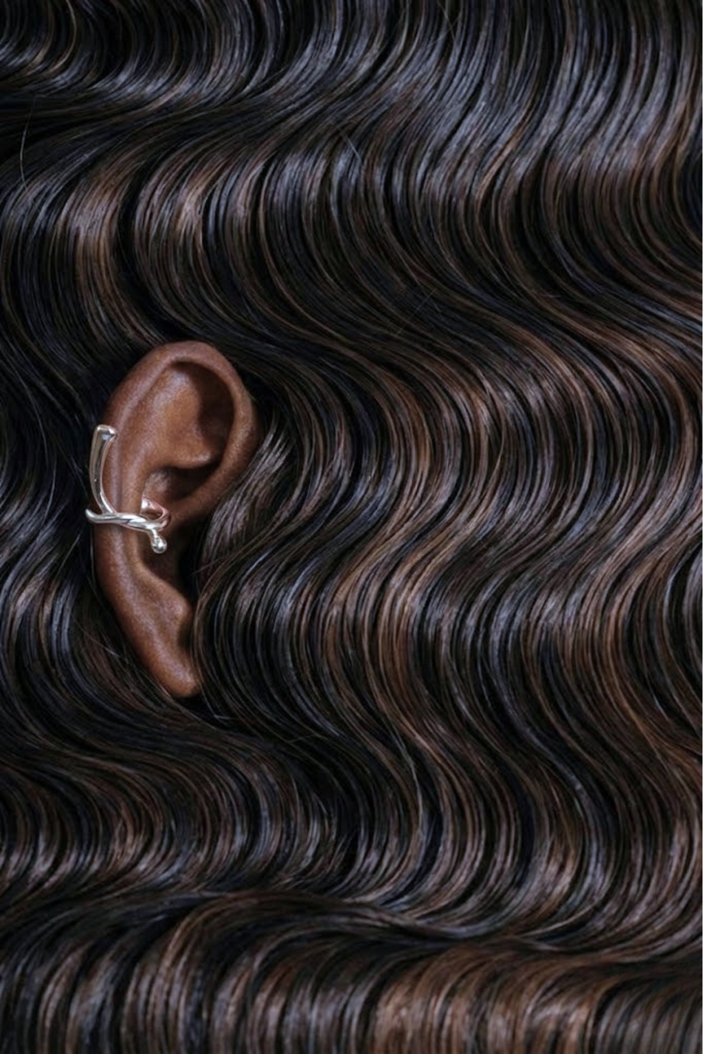 A chunky silver ear cuff clipped onto the ear, no piercing needed