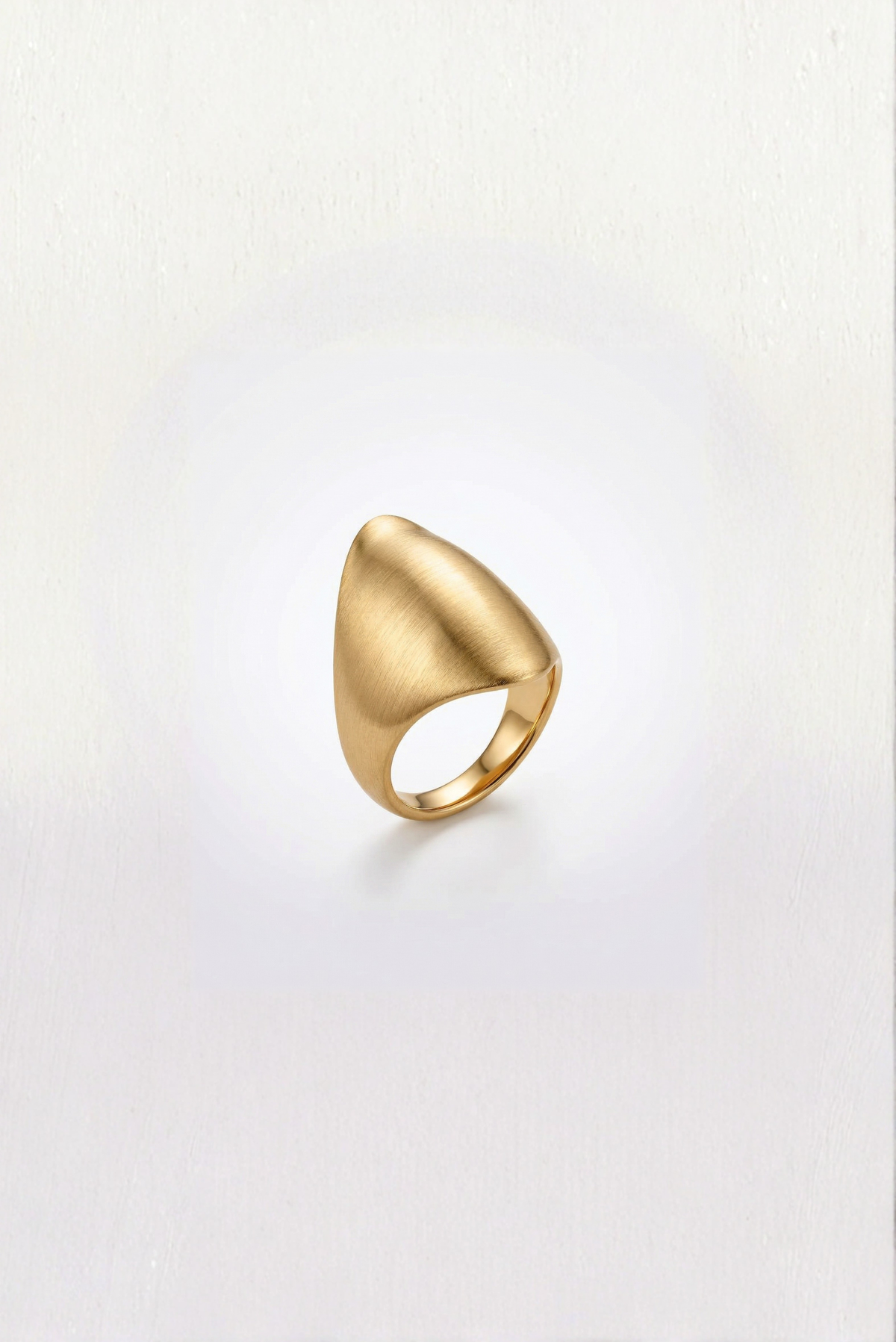 A chunky gold statement ring worn on the hand