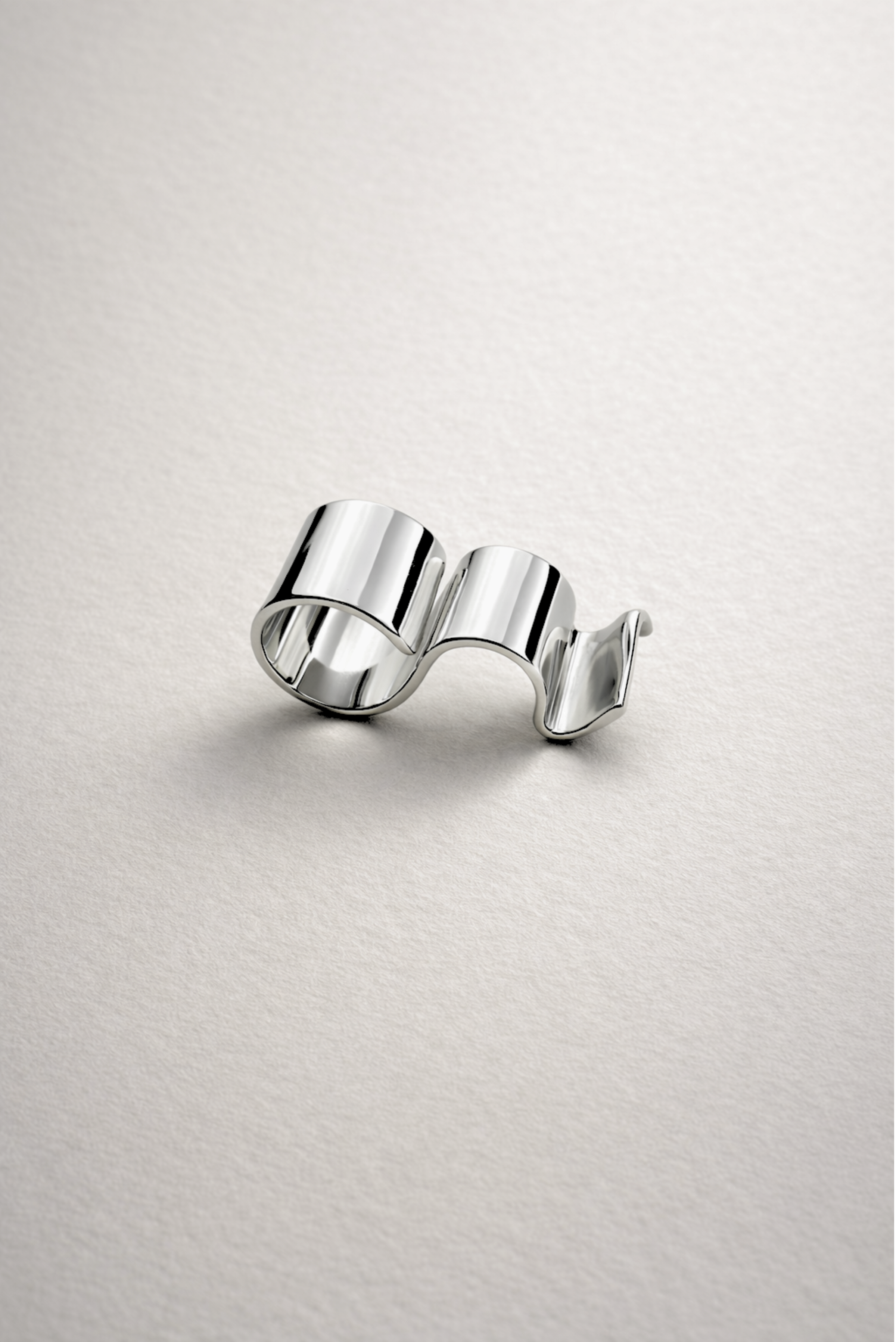 A maximalist silver multi-finger ring styled on the hand