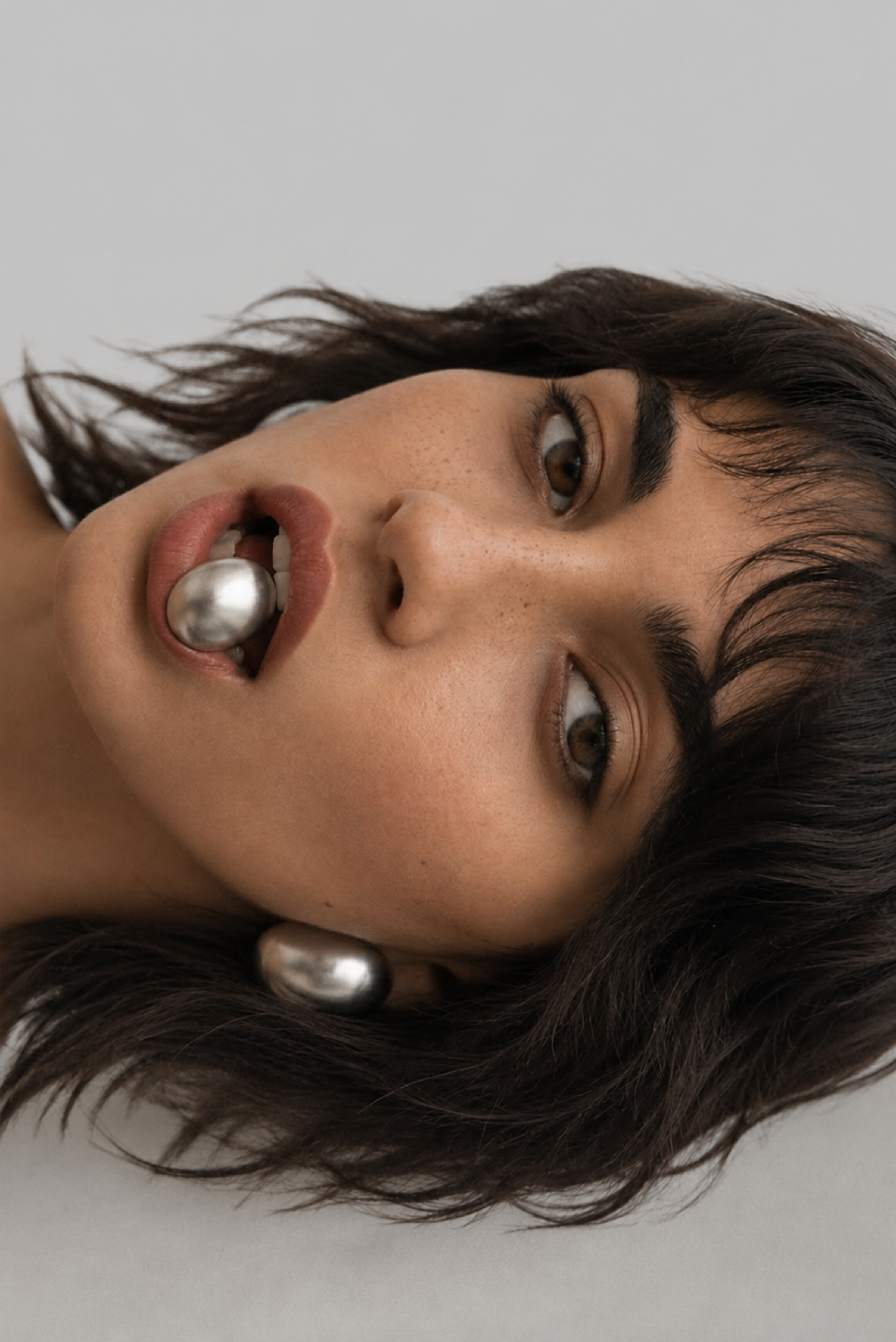 A pair of chunky gold statement earrings worn on the ears