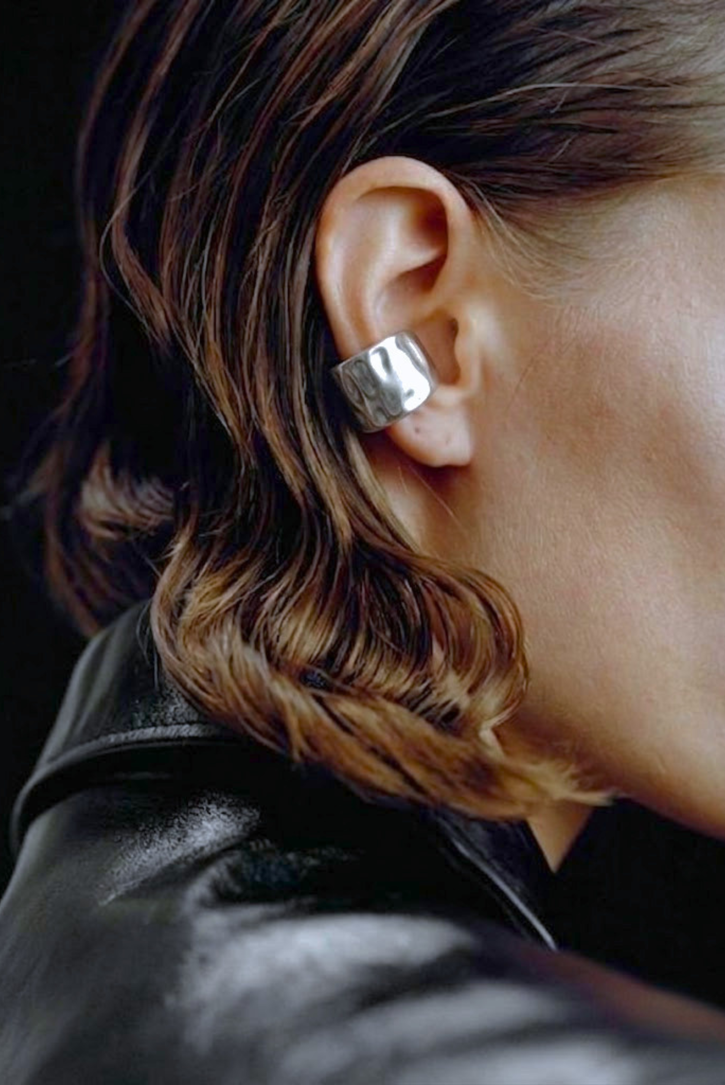 A model wearing a single silver ear cuff without a piercing