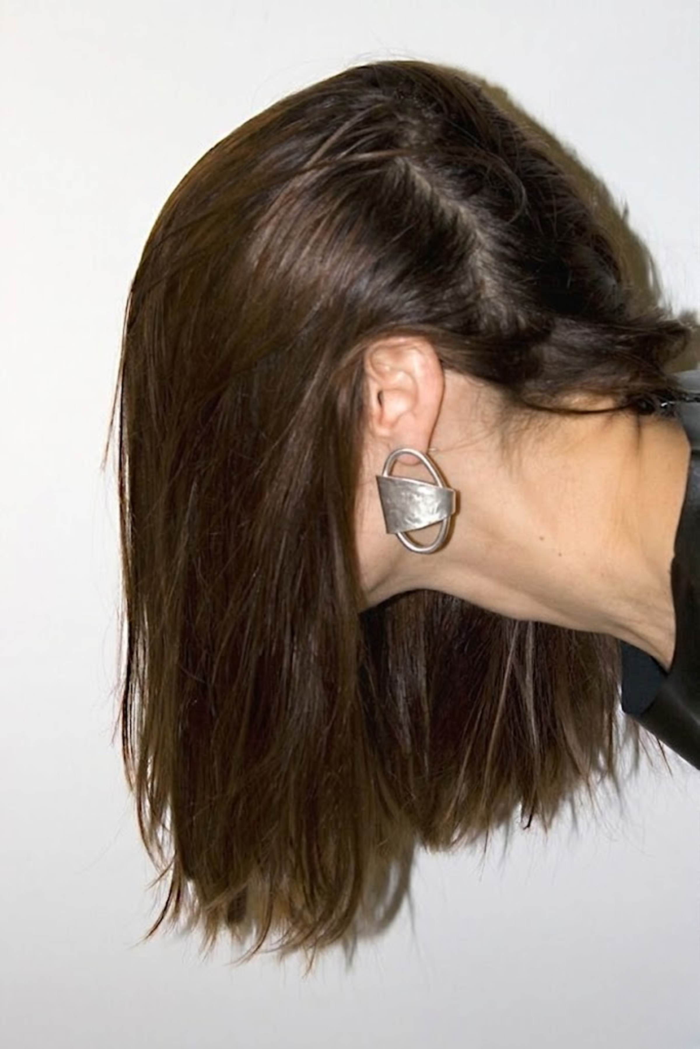 A pair of oversized gold geometric stud earrings worn on the ears