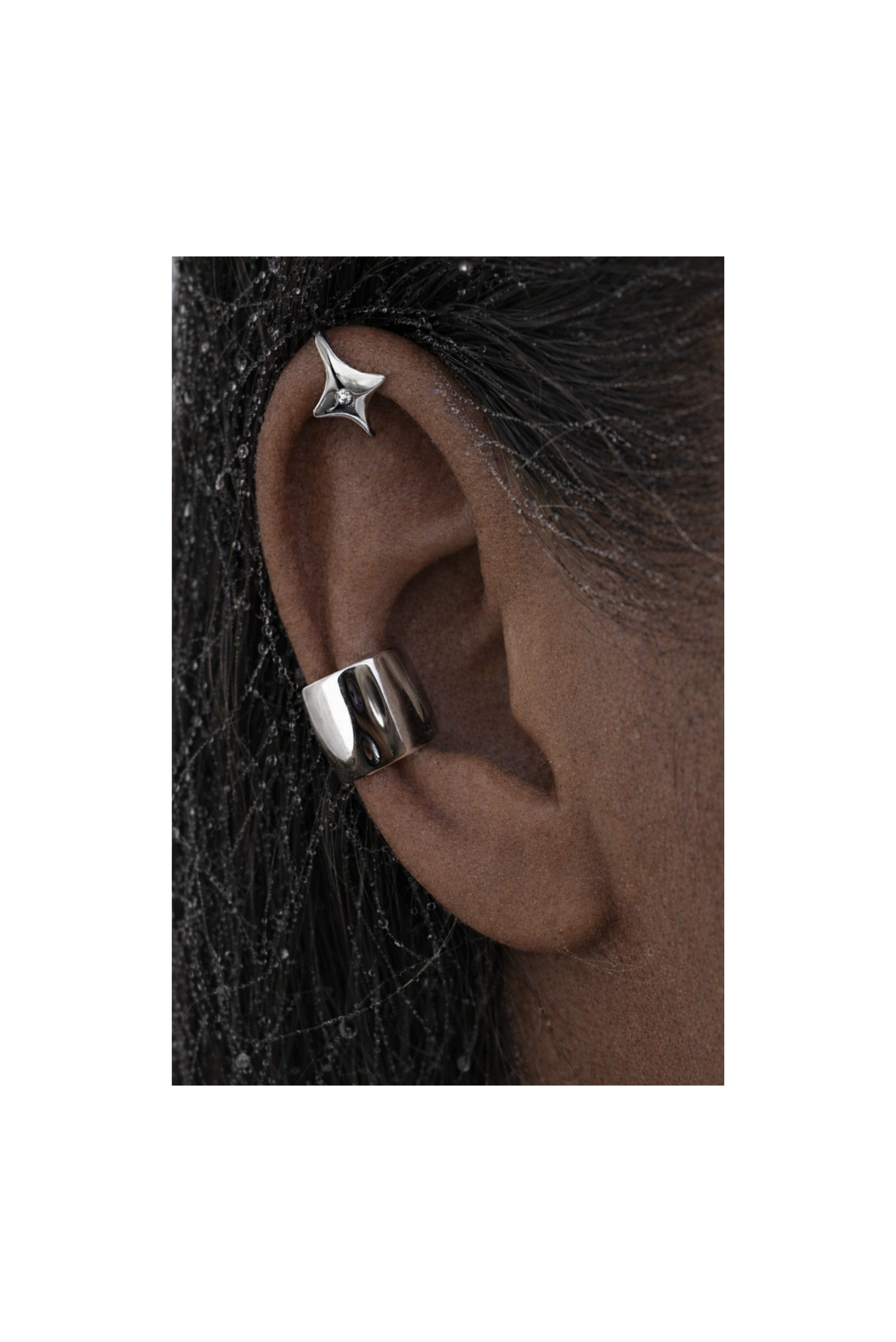 A two-piece silver ear cuff set with sparkling stones, worn on one ear